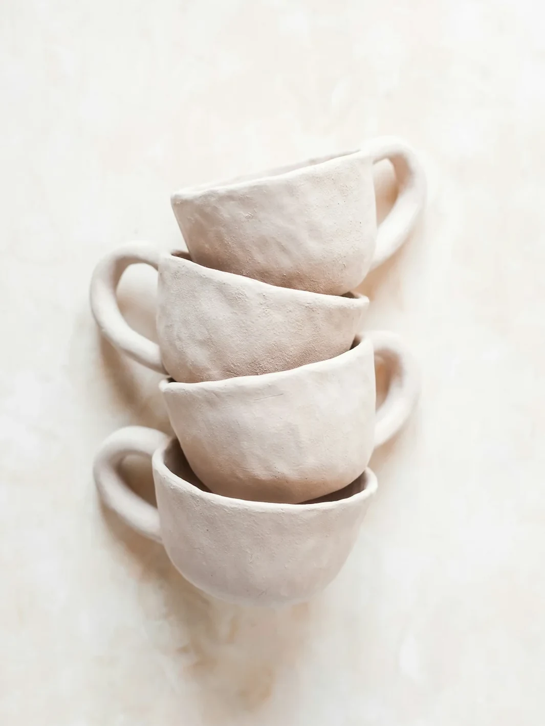 A stack of handmade cream ceramic cups